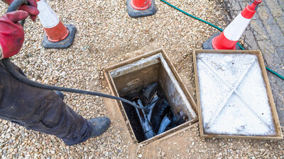 View of open manhole with drainage jetting equipment to unblock the drains